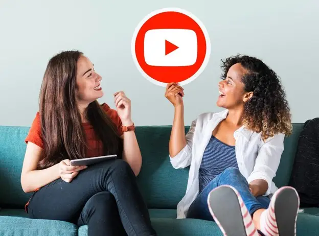 Two women holding a YouTube icon